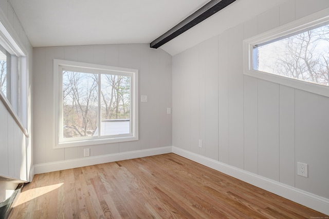 spare room featuring light wood-type flooring, vaulted ceiling with beams, and a healthy amount of sunlight