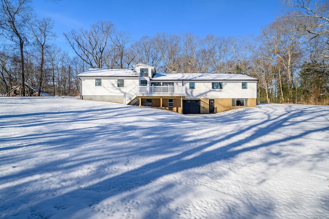 snow covered property with a garage and a wooden deck