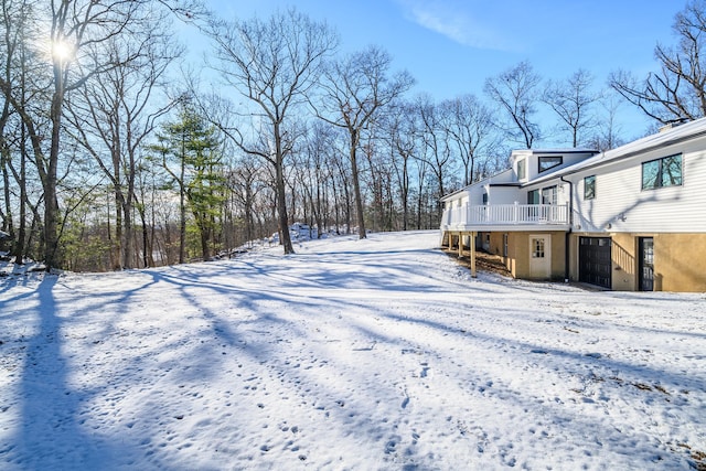 snowy yard featuring a deck and a garage