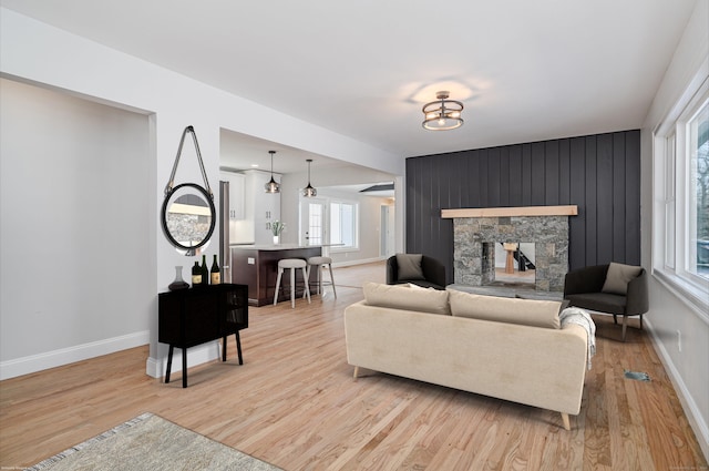 living room with a stone fireplace and light hardwood / wood-style flooring