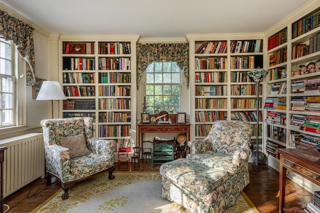 sitting room with wall of books, radiator heating unit, and crown molding