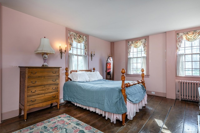 bedroom featuring multiple windows, hardwood / wood-style flooring, and radiator