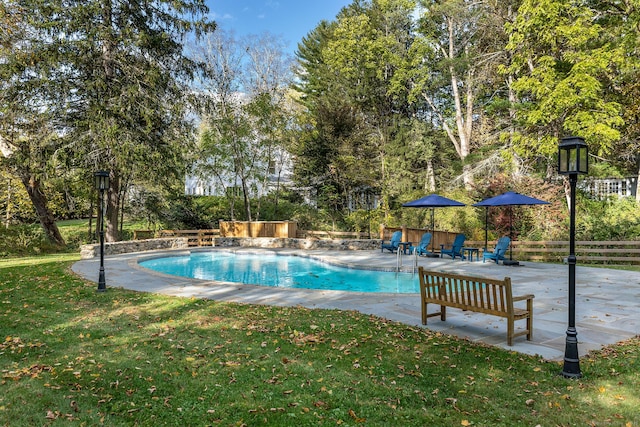 pool featuring a patio area, a yard, and fence