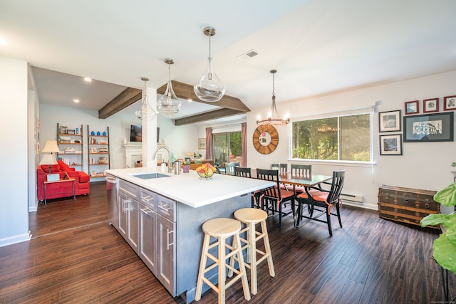 kitchen with hanging light fixtures, a center island with sink, a kitchen bar, dark hardwood / wood-style floors, and sink