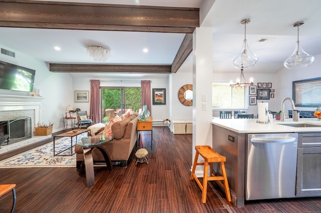 kitchen with beam ceiling, hanging light fixtures, stainless steel dishwasher, dark hardwood / wood-style floors, and a fireplace