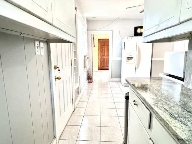 kitchen featuring white fridge with ice dispenser, white cabinetry, light stone countertops, and light tile patterned floors