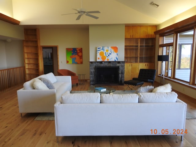 living room with ceiling fan, lofted ceiling, light wood-type flooring, and a fireplace