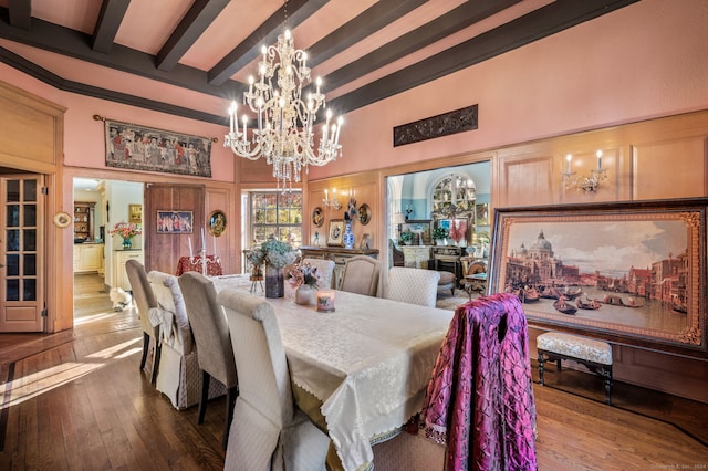 dining space with beam ceiling, hardwood / wood-style floors, a chandelier, and a high ceiling