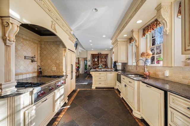 kitchen with cream cabinets, tasteful backsplash, dark stone countertops, and sink