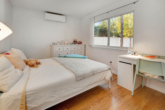 bedroom featuring light wood-type flooring and a wall unit AC