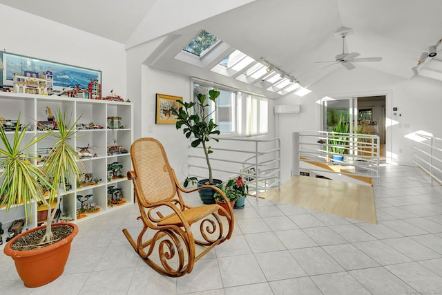 sitting room with lofted ceiling with skylight, light tile patterned flooring, and ceiling fan