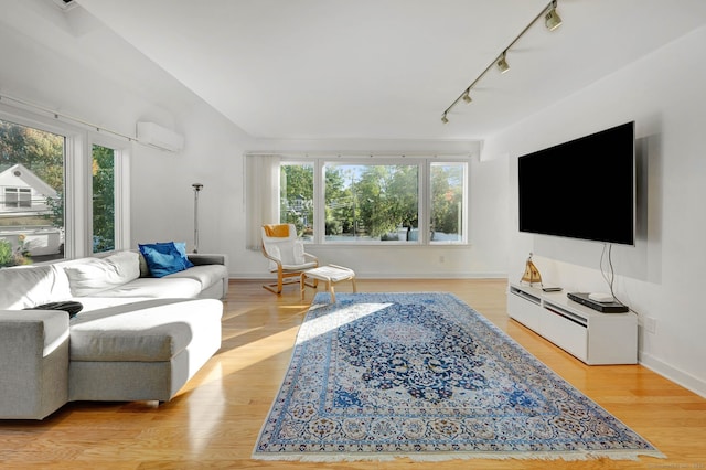 living room with an AC wall unit, light hardwood / wood-style flooring, and rail lighting