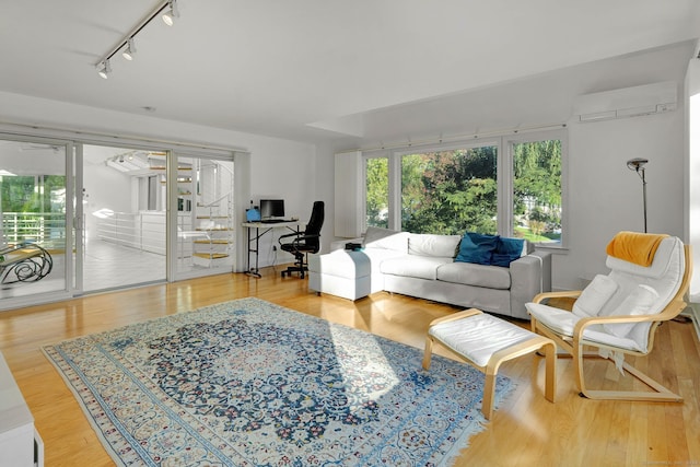 living room featuring track lighting, a wall unit AC, and light hardwood / wood-style floors