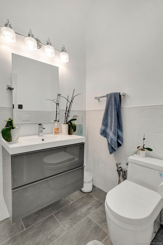 bathroom with vanity, toilet, tile walls, and tile patterned flooring