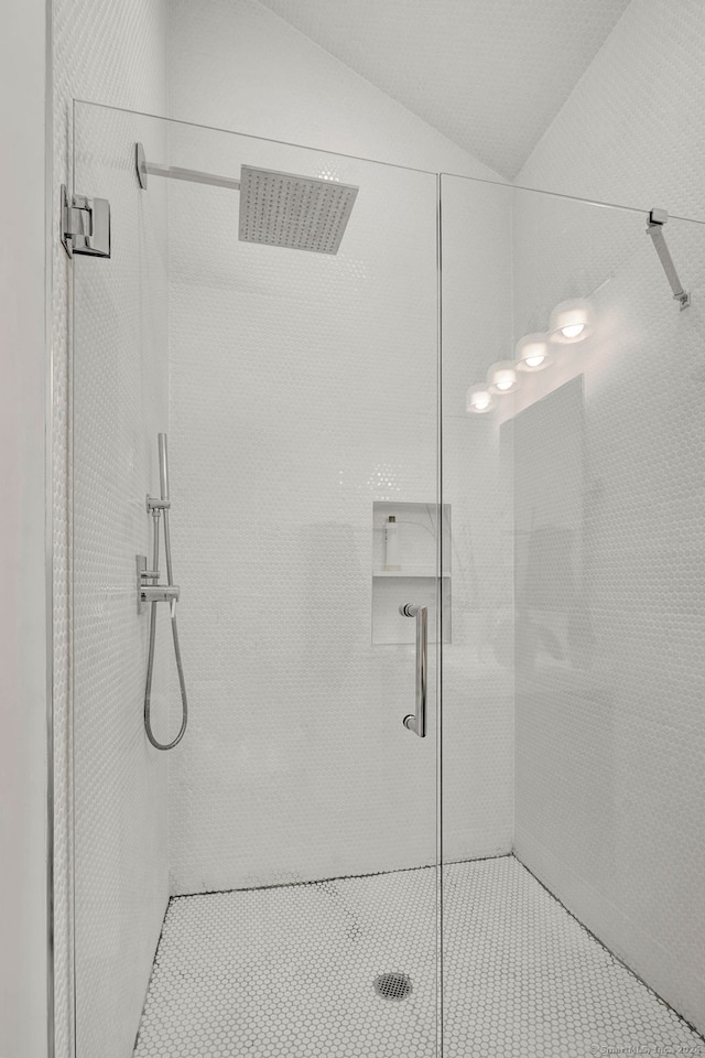 bathroom featuring a shower with door and vaulted ceiling