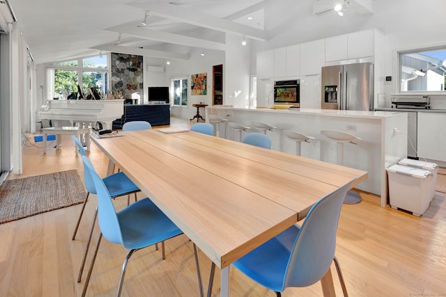 dining room with lofted ceiling with beams and light hardwood / wood-style floors