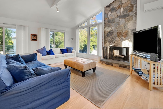 living room with a wall mounted air conditioner, light hardwood / wood-style flooring, high vaulted ceiling, and a fireplace