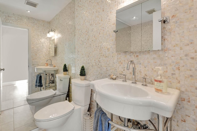 bathroom with tile patterned floors, toilet, backsplash, sink, and tile walls