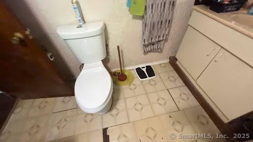 bathroom with toilet, marble finish floor, and vanity