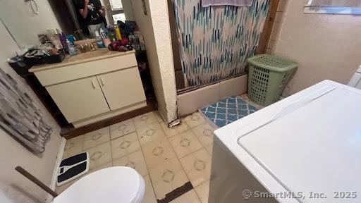 full bathroom with curtained shower, washer / clothes dryer, vanity, and toilet