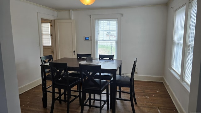 dining area featuring ornamental molding, a wealth of natural light, and dark wood-type flooring