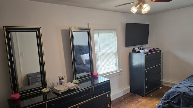 bedroom featuring baseboards, a ceiling fan, dark wood finished floors, and multiple windows