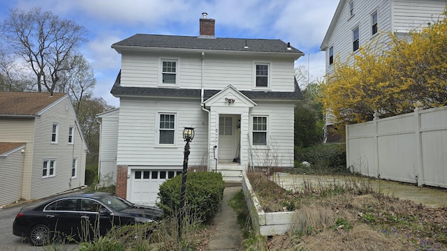 rear view of property with an attached garage, fence, a chimney, and roof with shingles