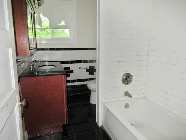 full bathroom featuring tiled shower / bath, vanity, tile patterned floors, toilet, and tile walls