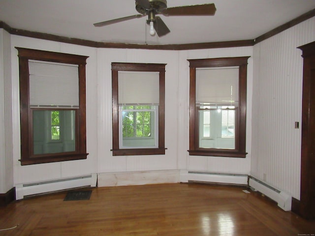 spare room with a baseboard heating unit, hardwood / wood-style flooring, ornamental molding, and ceiling fan