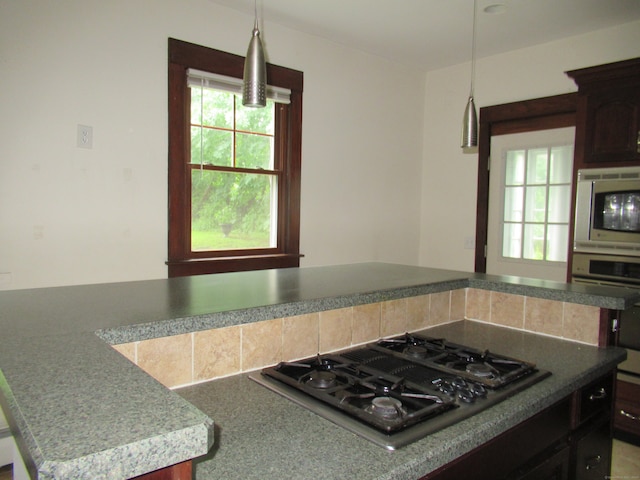 kitchen with a kitchen island, pendant lighting, appliances with stainless steel finishes, and dark brown cabinets