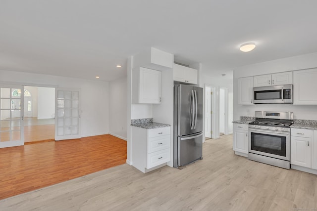 kitchen featuring white cabinetry, light hardwood / wood-style flooring, light stone counters, and appliances with stainless steel finishes