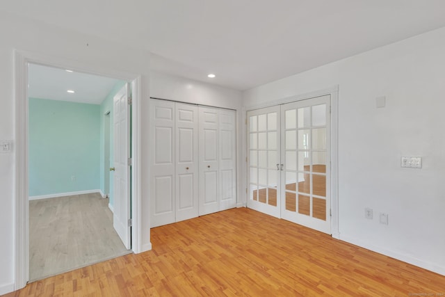 unfurnished bedroom with a closet, french doors, and light wood-type flooring