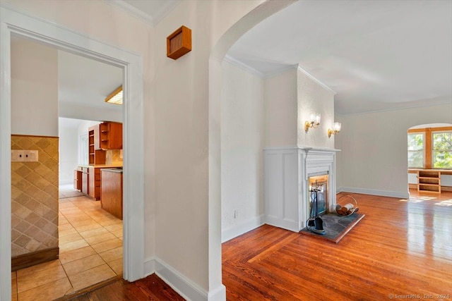 hall featuring crown molding, tile walls, and light hardwood / wood-style flooring