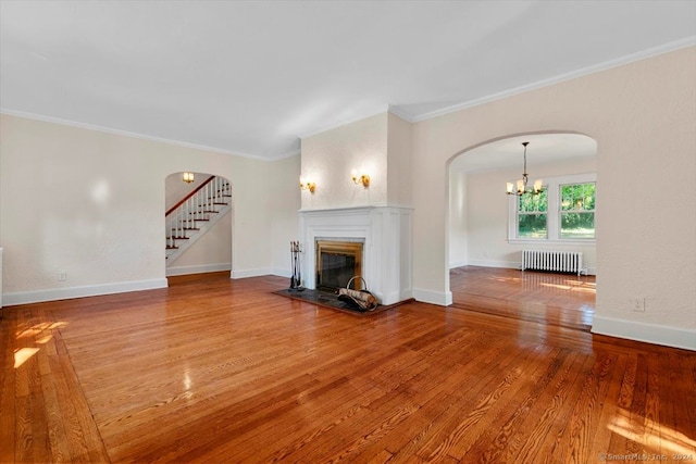 unfurnished living room with ornamental molding, an inviting chandelier, hardwood / wood-style floors, and radiator