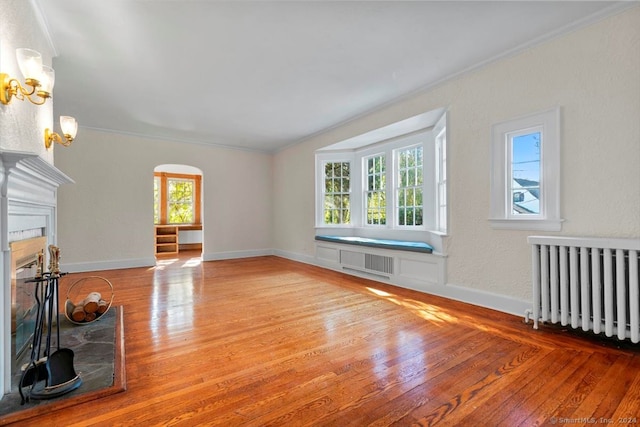 unfurnished living room featuring ornamental molding, wood-type flooring, and radiator