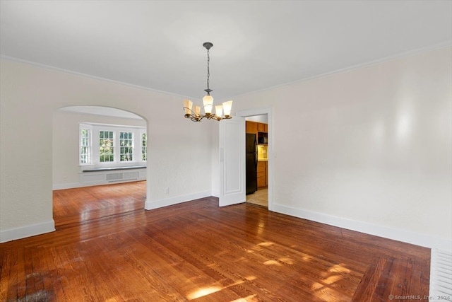 empty room featuring crown molding, a chandelier, and hardwood / wood-style floors