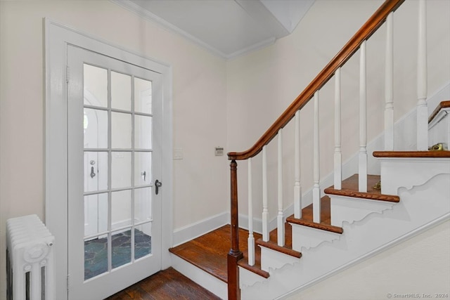 stairs featuring crown molding, radiator heating unit, and hardwood / wood-style flooring