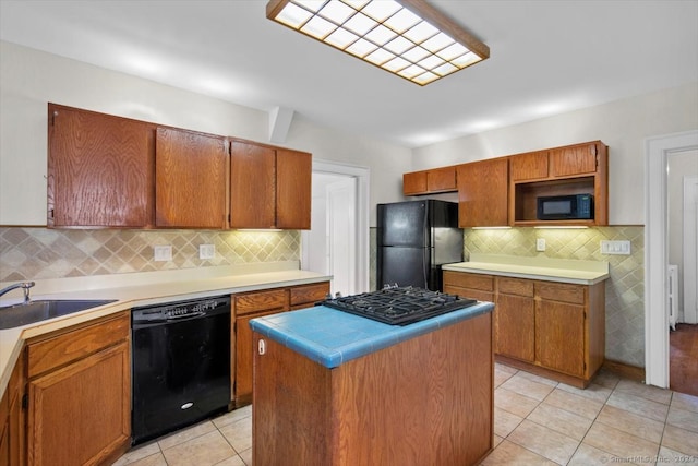 kitchen with a kitchen island, sink, black appliances, light tile patterned flooring, and tasteful backsplash