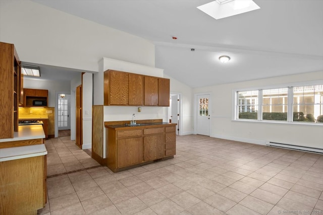 kitchen with baseboard heating, high vaulted ceiling, a skylight, and light tile patterned floors