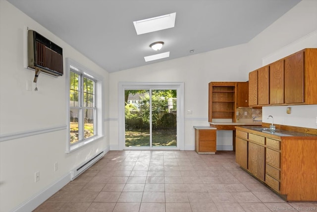 kitchen with sink, light tile patterned flooring, a baseboard heating unit, an AC wall unit, and vaulted ceiling with skylight