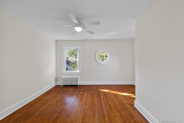 unfurnished room featuring dark wood-type flooring, ceiling fan, and radiator