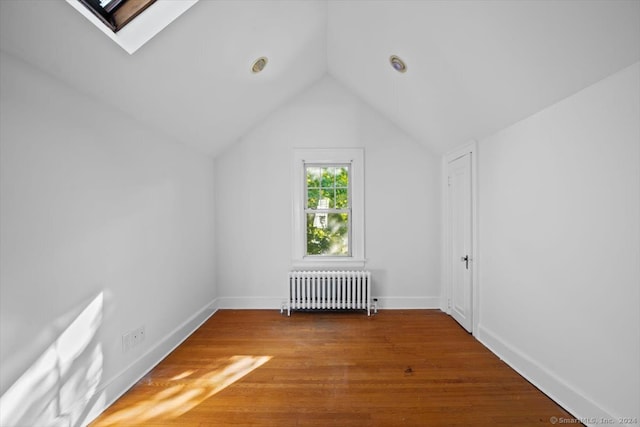 bonus room featuring radiator, vaulted ceiling with skylight, and hardwood / wood-style floors