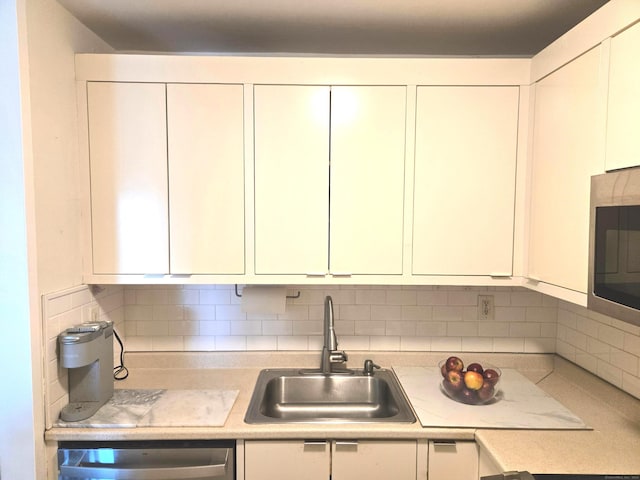 kitchen with tasteful backsplash, white cabinetry, sink, and stainless steel appliances