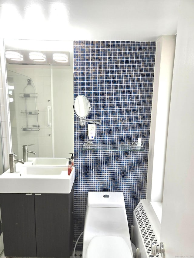 bathroom featuring vanity, toilet, tile walls, and a tile shower