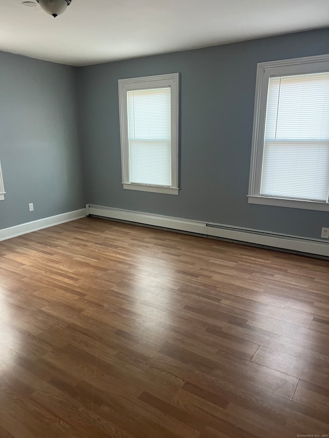 empty room featuring baseboard heating and dark hardwood / wood-style flooring