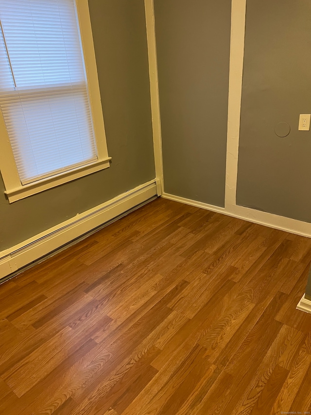 empty room featuring hardwood / wood-style flooring and a baseboard heating unit