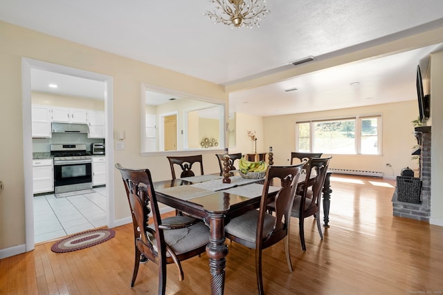 dining space featuring baseboard heating and light wood-type flooring