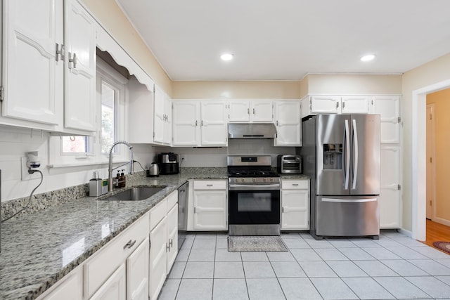 kitchen featuring light stone counters, appliances with stainless steel finishes, white cabinetry, light tile patterned flooring, and sink