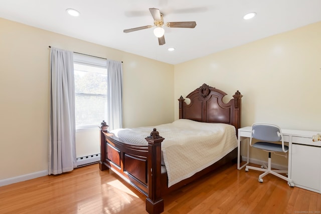 bedroom featuring built in desk, ceiling fan, light hardwood / wood-style flooring, and a baseboard heating unit