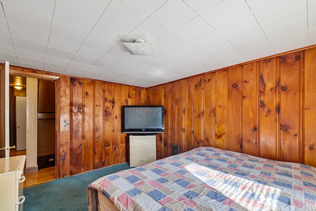 bedroom featuring wood walls and carpet